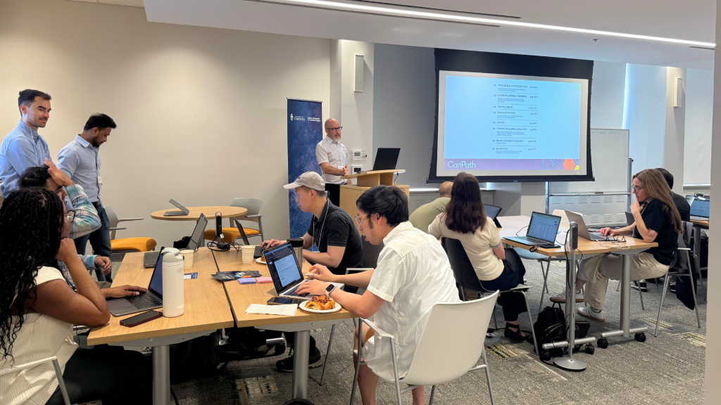 Workshop attendees sitting at tables, working on their laptops. 