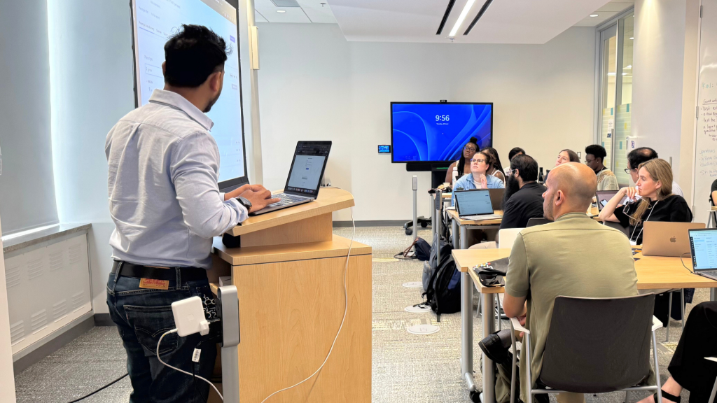 Sangram presenting at the podium to the attendees in the audience.