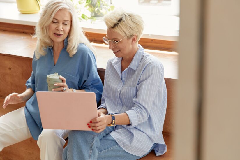 Two women talking and looking at a laptop.